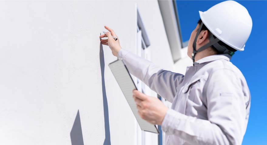 A man inspecting the outer wall of a building